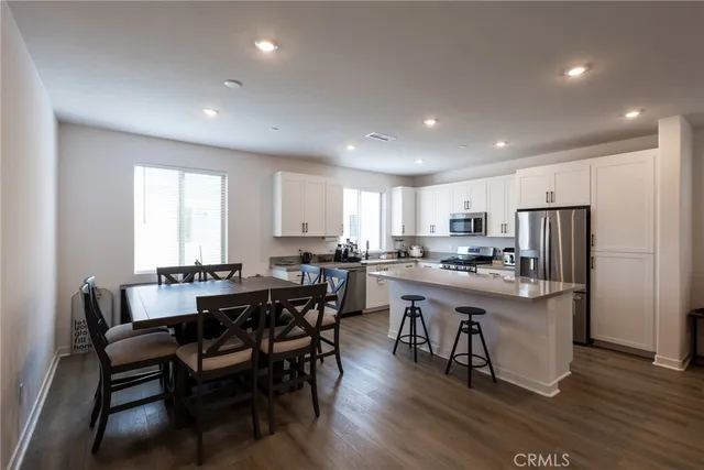 a kitchen with stainless steel appliances a dining table chairs and wooden floor