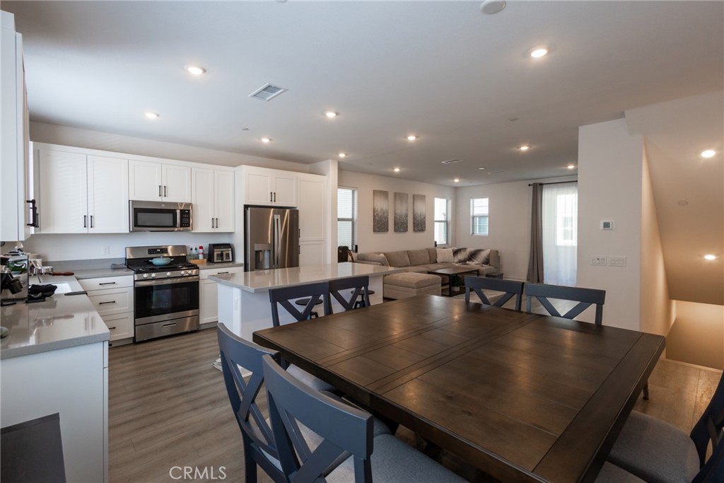 2640 Sprout Lane, Unit 104 Corona, CA 92883 - Photo 5 of 20 a large kitchen with stainless steel appliances granite countertop a stove a sink a dining table and chairs