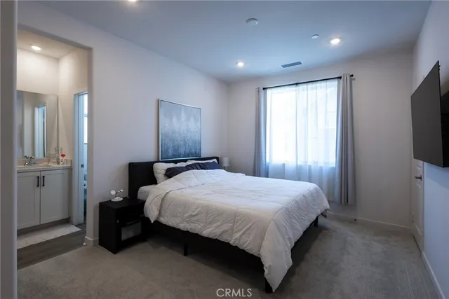 a bedroom with a bed and a flat tv screen on dresser