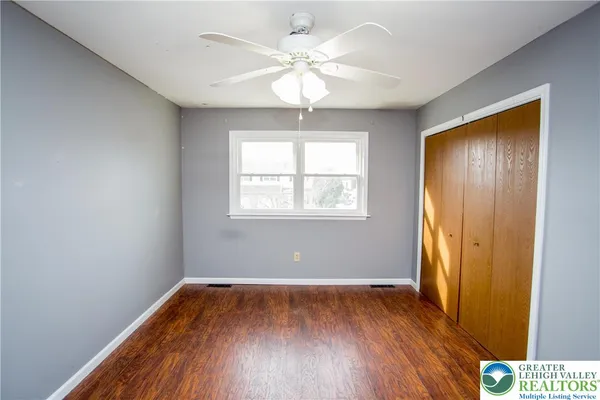 a view of empty room with wooden floor and fan