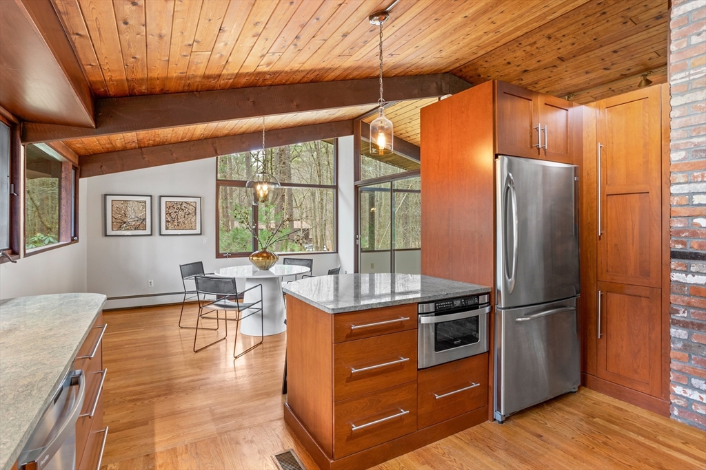 69 Long Ridge Road Carlisle, MA 01741 - Photo 11 of 42 a kitchen with stainless steel appliances granite countertop a refrigerator a stove and a dining table with wooden floor