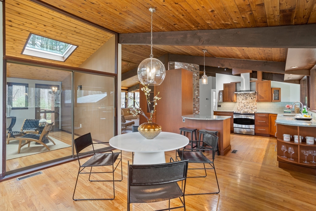 69 Long Ridge Road Carlisle, MA 01741 - Photo 14 of 42 a dining room with wooden floor a chandelier a glass table and chairs
