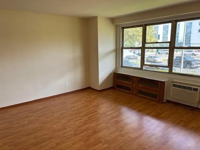 a view of an empty room with a window and wooden floor