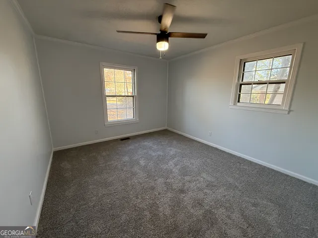 an empty room with windows and fan