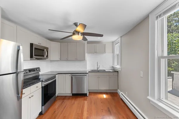 a kitchen with stainless steel appliances a stove a refrigerator a sink a microwave oven with cabinets and wooden floor
