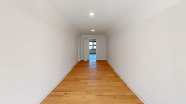 a view of a hallway with wooden floor and a rug