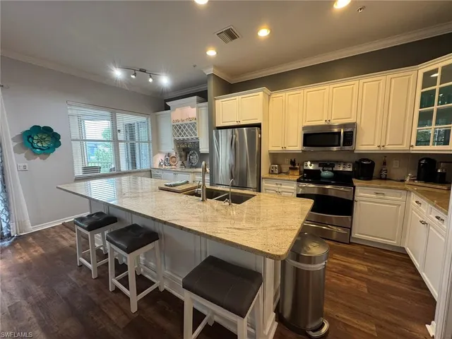 a kitchen with stainless steel appliances granite countertop a stove top oven a refrigerator a sink and a dining table with wooden floor