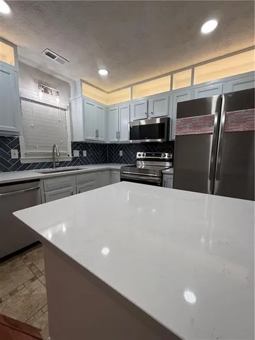 a kitchen with stainless steel appliances a refrigerator sink and microwave