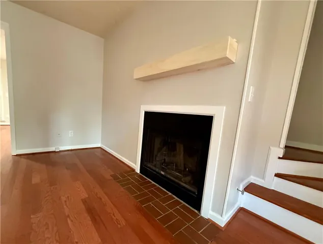 a view of an empty room with wooden floor and a fireplace