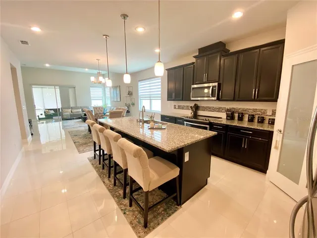 a kitchen with kitchen island granite countertop a sink a counter top space appliances and cabinets
