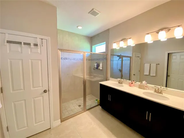 a bathroom with a double vanity sink mirror and shower