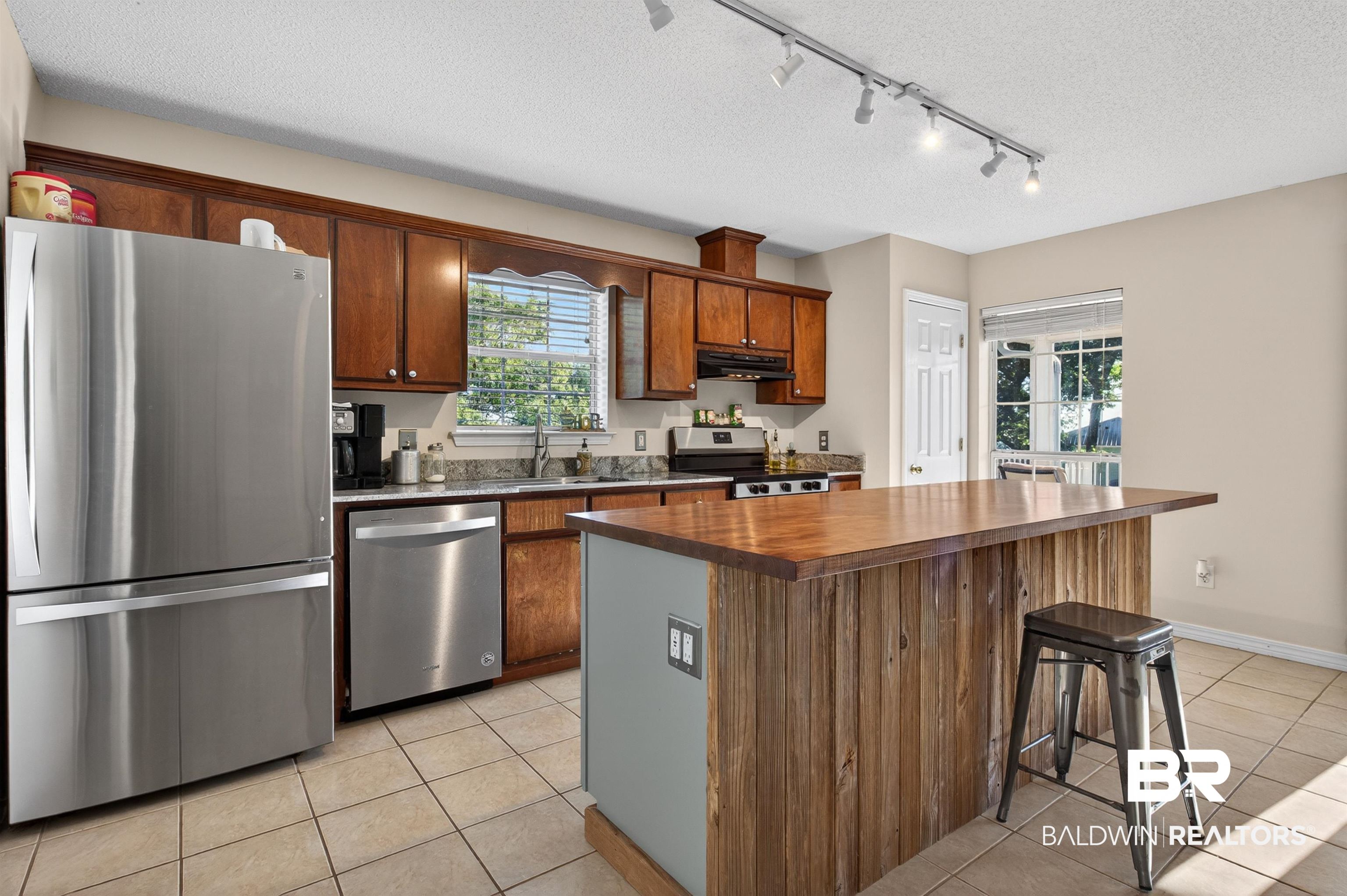 9624 North Bay Street Foley, AL 36535 - Photo 11 of 59 Kitchen featuring wood cabinetry, stainless steel appliances, granite countertops, and tile flooring