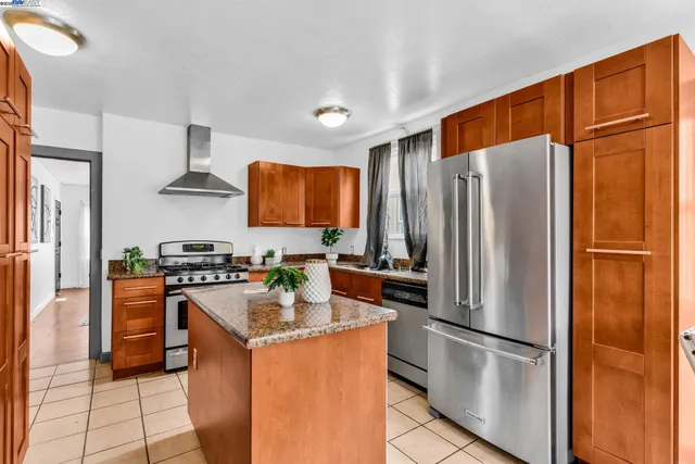 a kitchen with stainless steel appliances granite countertop a refrigerator a stove a sink a dining table and chairs