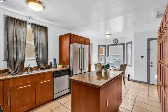 a kitchen with stainless steel appliances granite countertop a table chairs and a refrigerator
