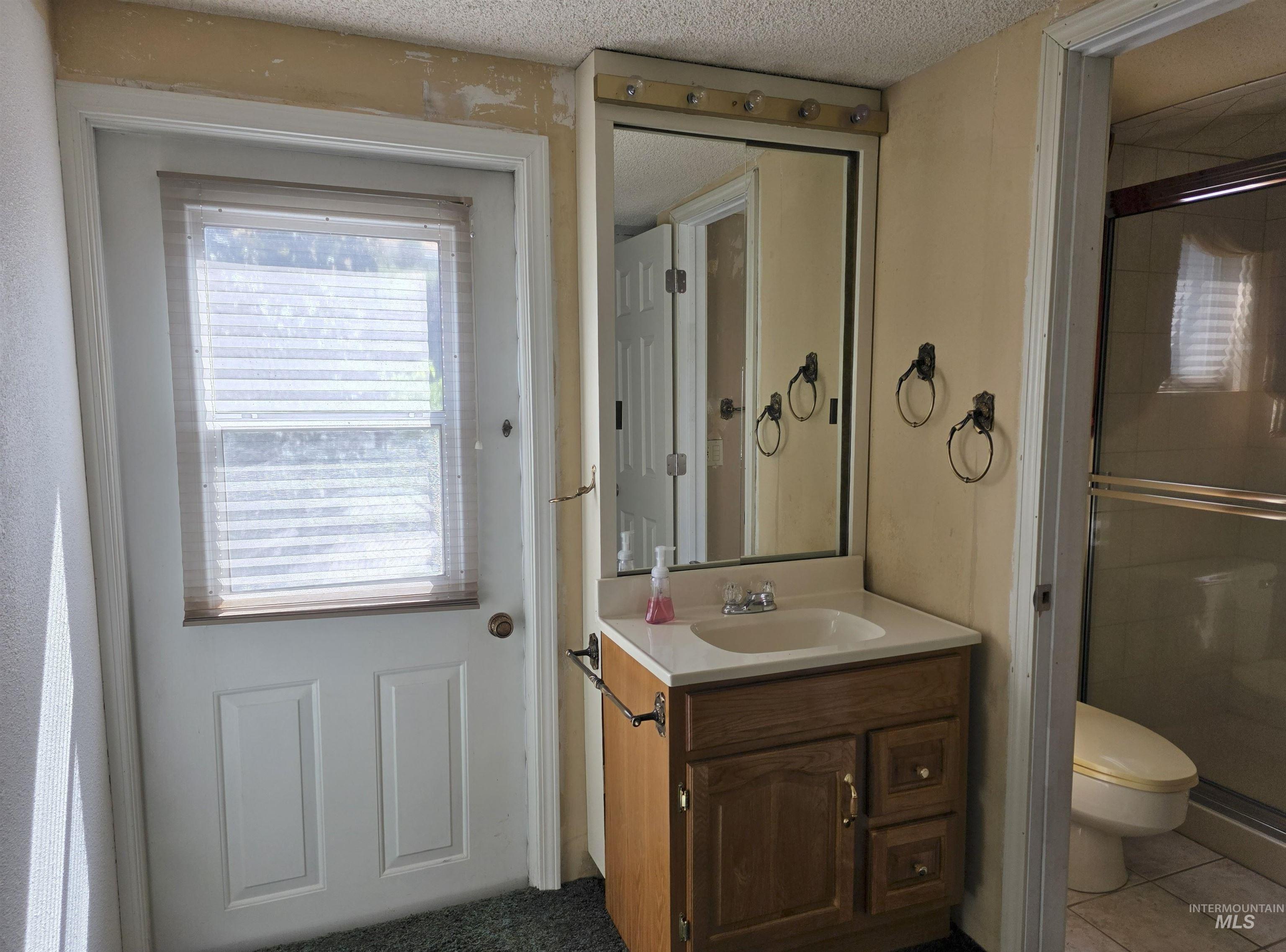 209 Harding Street Asotin, WA 99402 - Photo 18 of 29 Full bathroom with a stall shower, vanity, a textured ceiling, and tile patterned floors