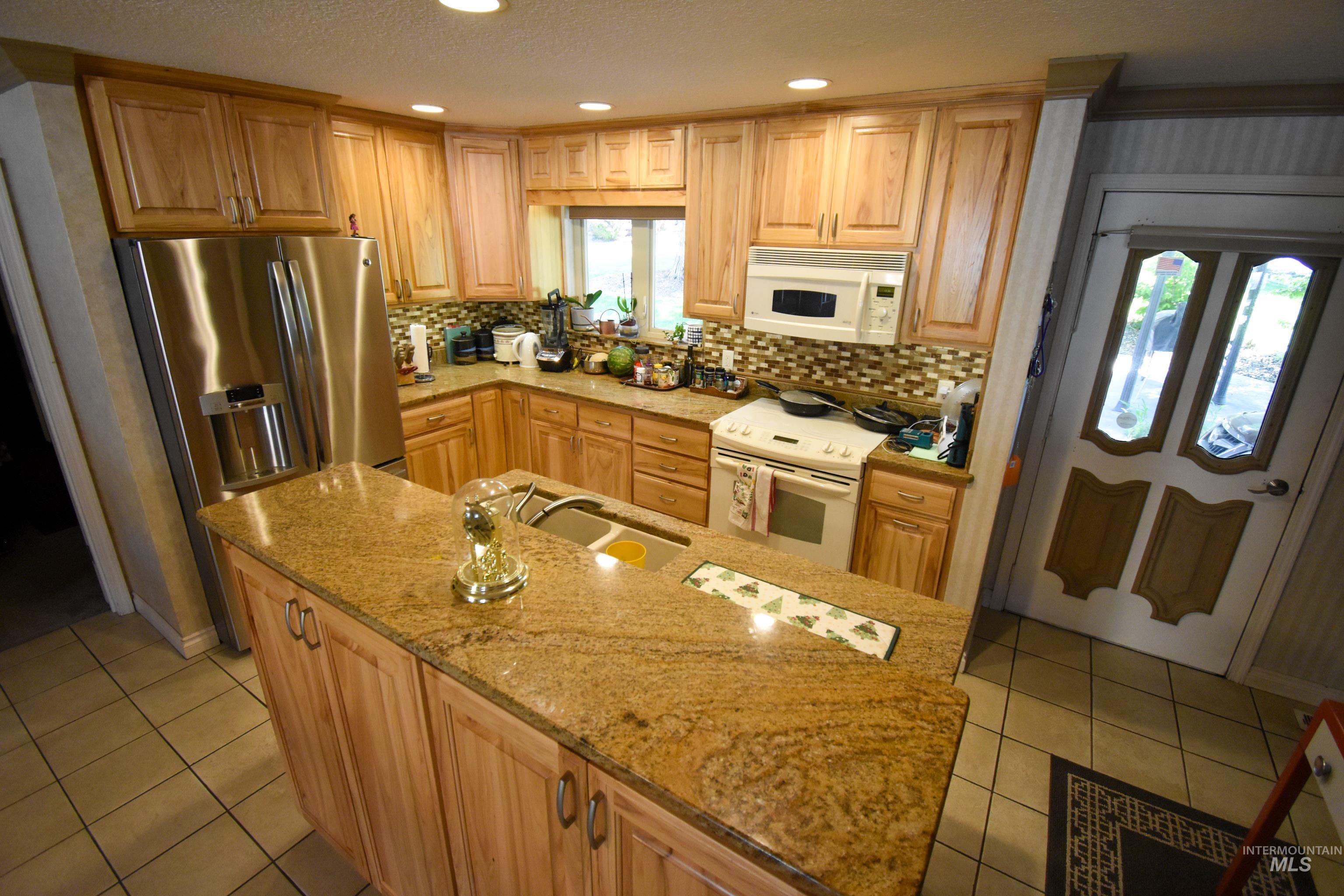 209 Harding Street Asotin, WA 99402 - Photo 6 of 29 Kitchen with backsplash, white appliances, recessed lighting, light tile patterned flooring, and light stone countertops