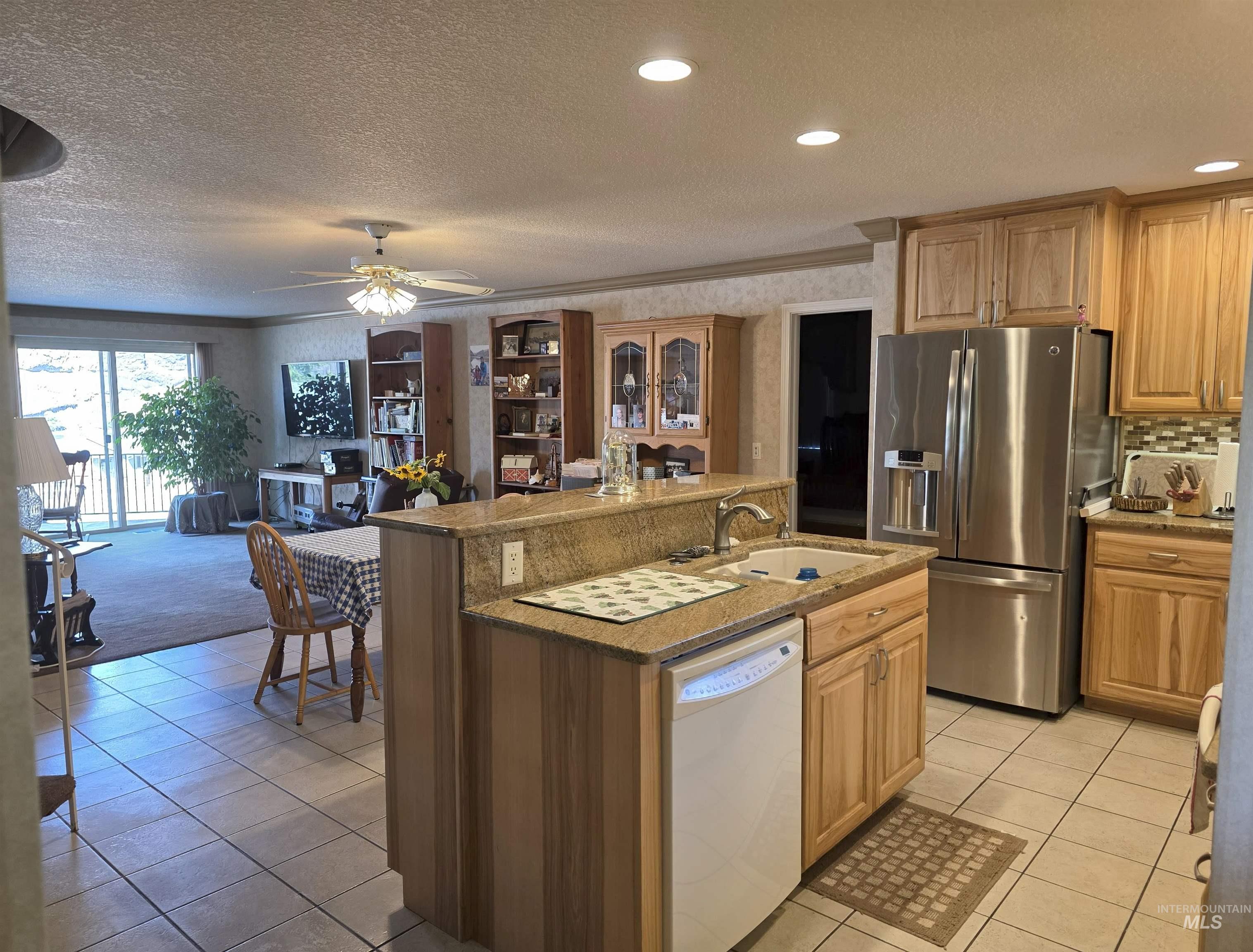 209 Harding Street Asotin, WA 99402 - Photo 7 of 29 Kitchen featuring light tile patterned floors, stainless steel refrigerator with ice dispenser, dishwasher, a textured ceiling, and a kitchen island with sink