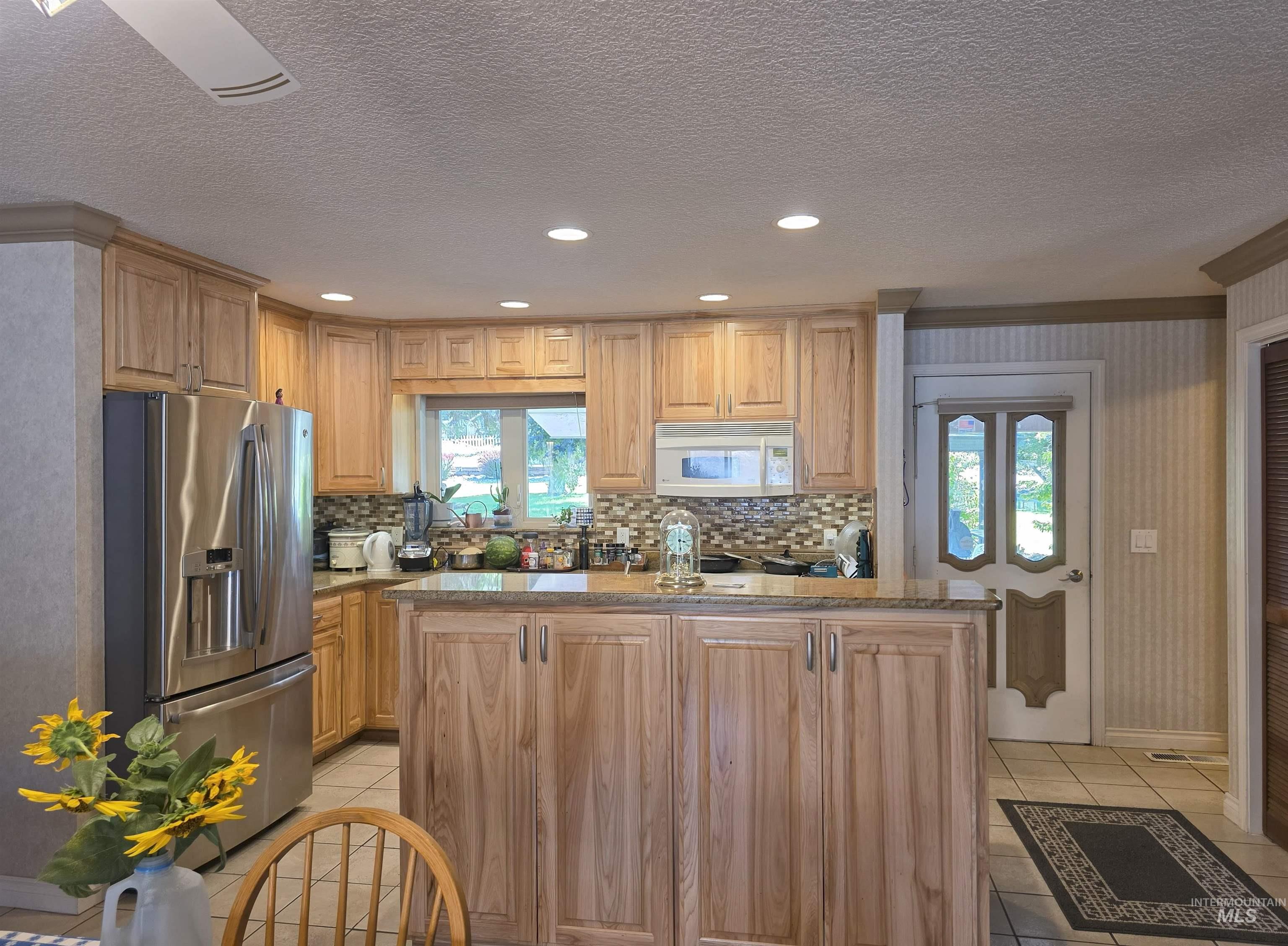 209 Harding Street Asotin, WA 99402 - Photo 8 of 29 Kitchen featuring stainless steel refrigerator with ice dispenser, recessed lighting, white microwave, a textured ceiling, and light tile patterned floors