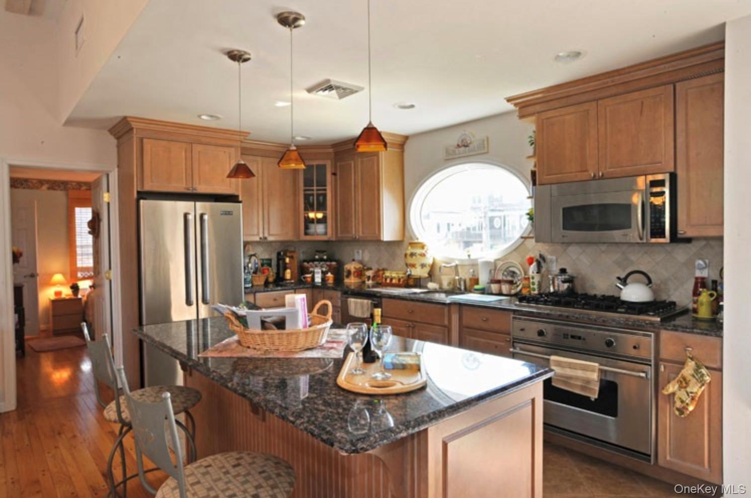 900 Dune Road Westhampton Beach, NY 11978 - Photo 4 of 14 a kitchen with stainless steel appliances granite countertop a stove refrigerator and cabinets