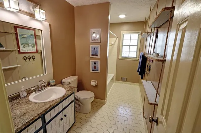 a bathroom with a sink a toilet a mirror and shower