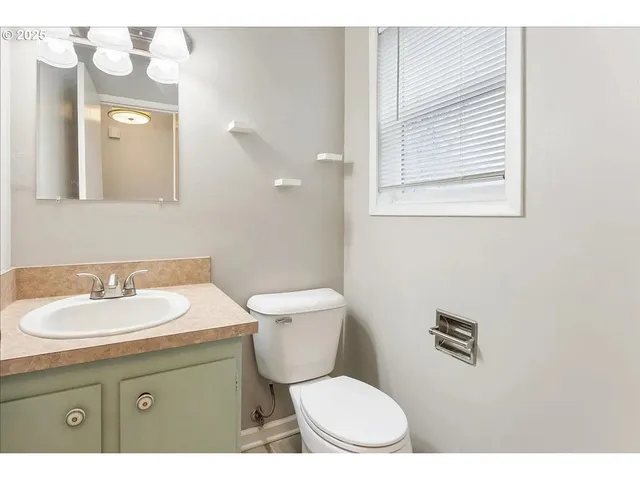 a bathroom with a toilet sink vanity and mirror