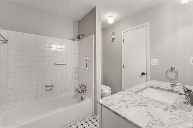 a bathroom with a granite countertop sink a mirror and a bathtub