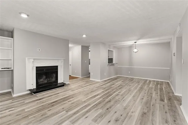 a view of an empty room with wooden floor fireplace and a window