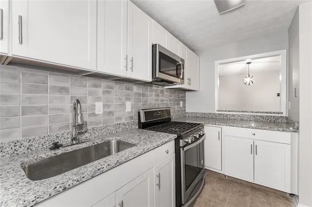 a kitchen with granite countertop white cabinets stainless steel appliances and a sink