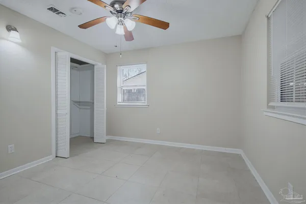 an empty room with chandelier fan and windows