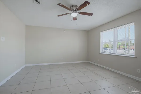 an empty room with windows and ceiling fan