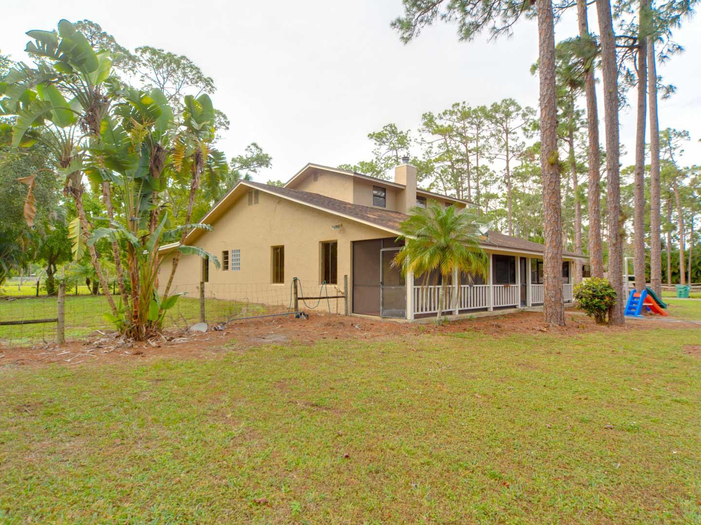 2477 West G Road Loxahatchee, FL 33470 - Photo 7 of 61 a front view of a house with a garden and tree