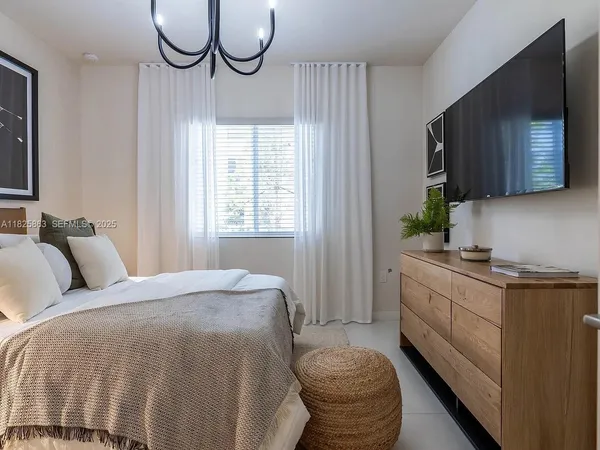 a bed room with a bed television and a window