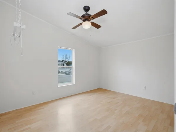 an empty room with ceiling fan and window