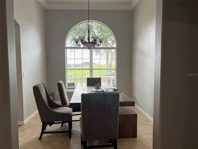 a view of a dining room with furniture a chandelier and a window