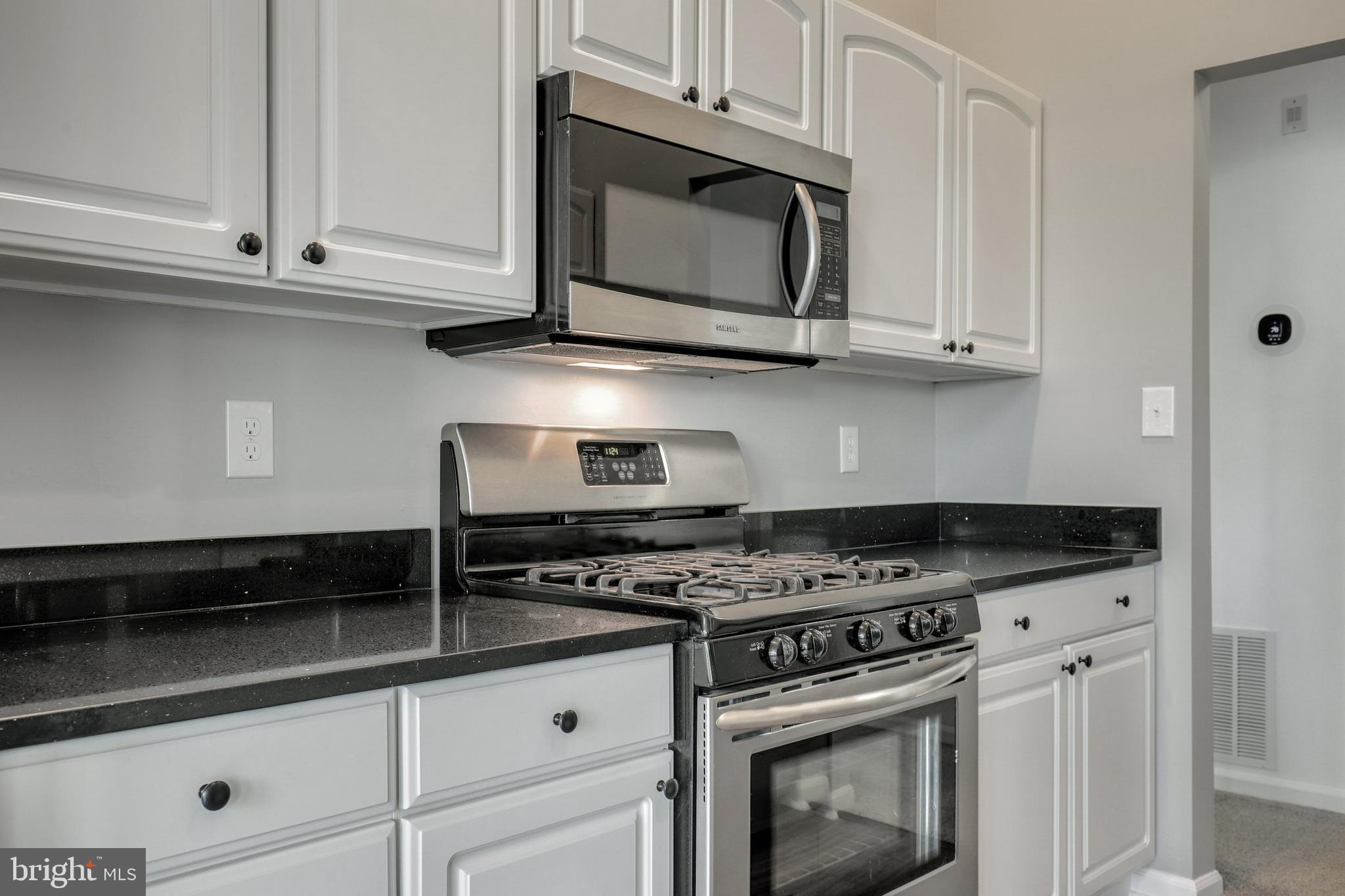 2444 Blue Spring Court, Unit 303 Odenton, MD 21113 - Photo 8 of 33 a kitchen with granite countertop white cabinets and appliances