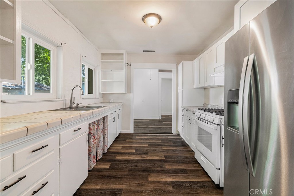 1617 Hemlock Street Chico, CA 95928 - Photo 8 of 60 a large white kitchen with granite countertop a sink and stainless steel appliances
