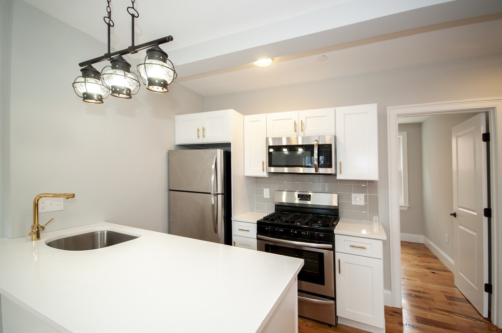 a kitchen with a refrigerator a sink and white cabinets
