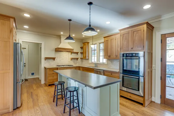 a kitchen with kitchen island granite countertop a sink cabinets and stainless steel appliances