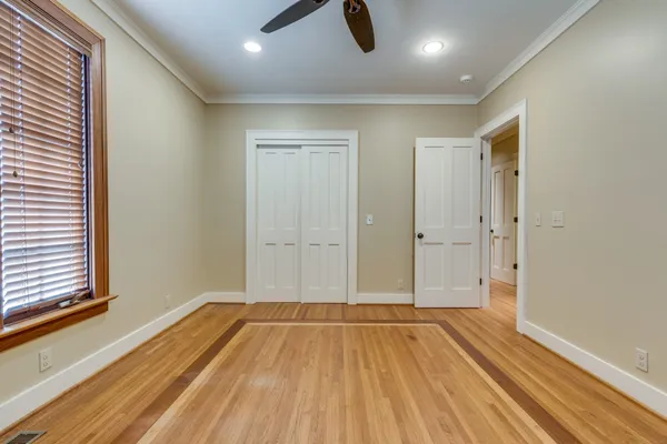 an empty room with wooden floor fan and windows