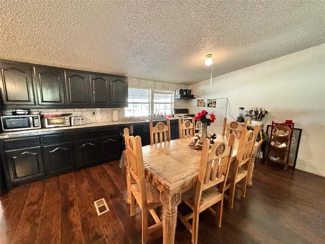 a kitchen with stainless steel appliances granite countertop a sink a stove a dining table and chairs