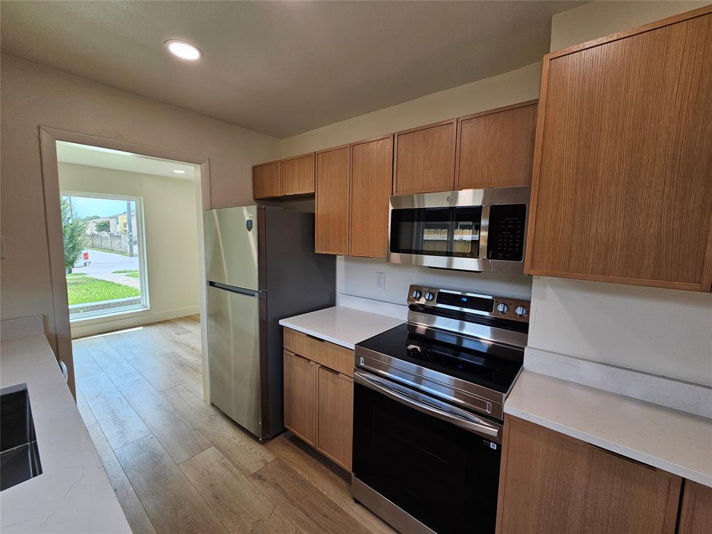 1725 R Avenue, Unit 1727 Plano, TX 75074 - Photo 6 of 20 Modern kitchen featuring wood-finish cabinetry, stainless steel appliances, and white countertops