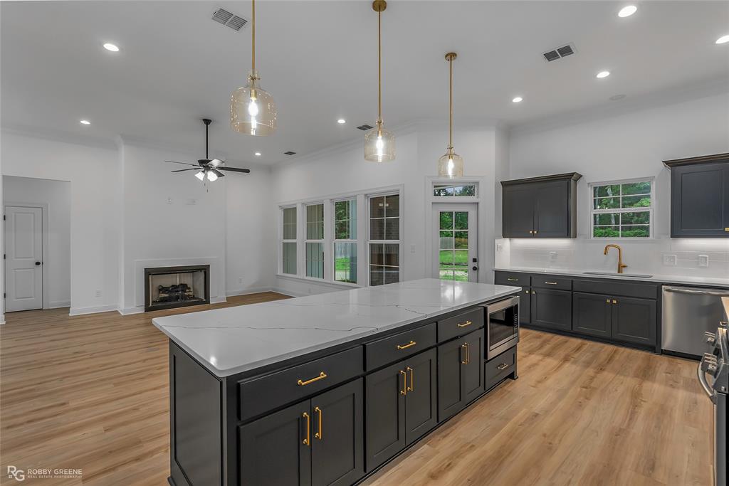 231 Ramsey Road Stonewall, LA 71078 - Photo 11 of 39 a kitchen with a stove center island a sink cabinets and wooden floor