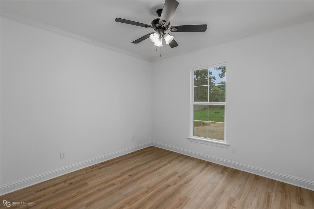 231 Ramsey Road Stonewall, LA 71078 - Photo 26 of 39 an empty room with wooden floor chandelier fan and windows