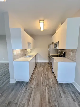 a living room with stainless steel appliances kitchen island granite countertop wooden floors and a sink