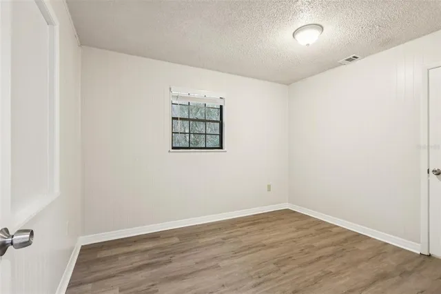 an empty room with wooden floor and window