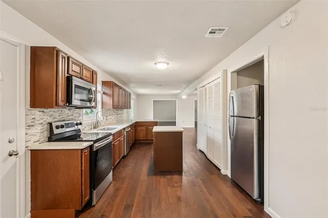 a kitchen with stainless steel appliances granite countertop lots of counter top space and wooden floor