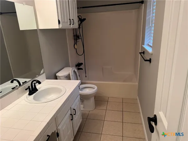 an empty room with a chandelier fan and windows