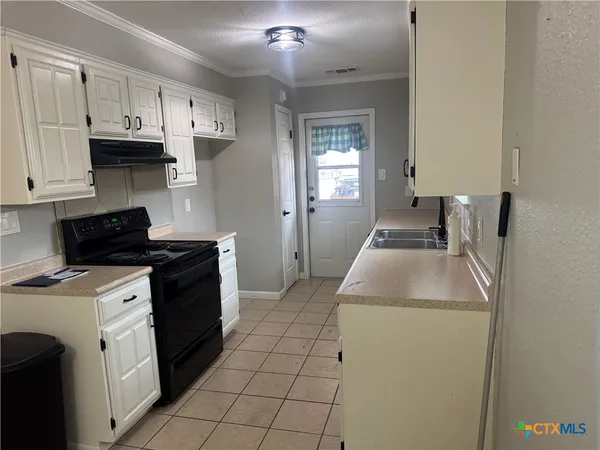 a kitchen with granite countertop a sink a stove and cabinets