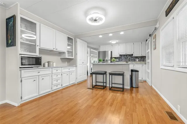 a kitchen with stainless steel appliances granite countertop a stove top oven a sink dishwasher and white cabinets with wooden floor