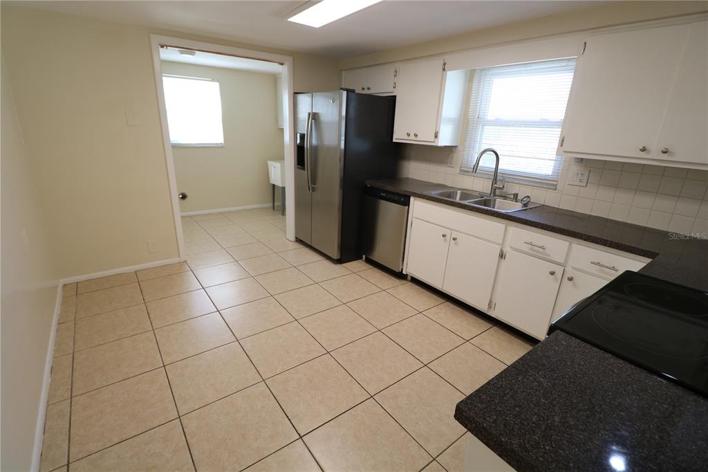 7825 Birchwood Drive Port Richey, FL 34668 - Photo 12 of 43 a kitchen with stainless steel appliances a refrigerator sink and cabinets